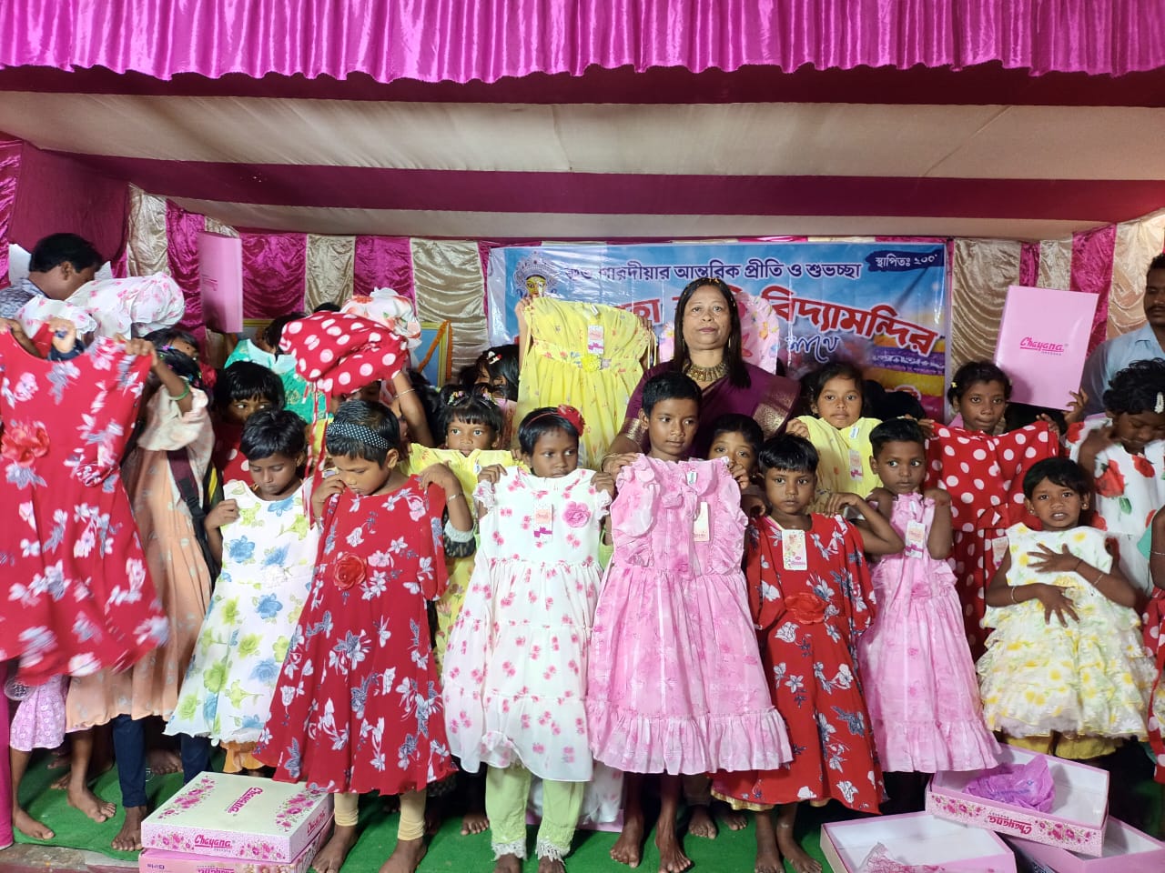 Smiling children holding up their new dresses at a community programme